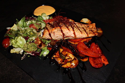 Salmon steak with red pesto grilled vegetables, herb salad and Hollandaise sauce